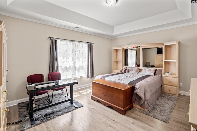 bedroom featuring a raised ceiling and light wood-type flooring