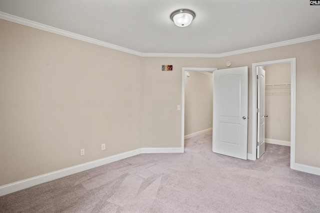 unfurnished bedroom with crown molding, a walk in closet, light colored carpet, and a closet