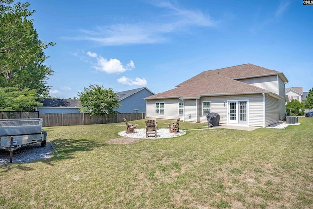 rear view of property with a yard, central AC, and an outdoor fire pit