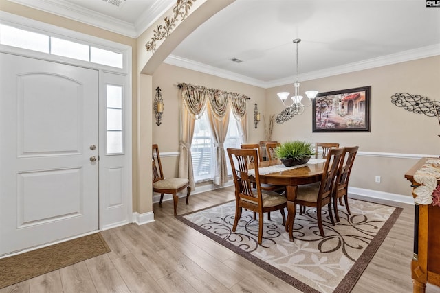 dining area with crown molding, a chandelier, and light hardwood / wood-style flooring