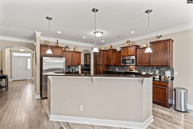 kitchen featuring a kitchen island, appliances with stainless steel finishes, and decorative light fixtures