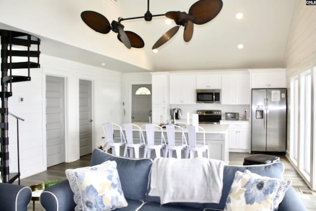 living room featuring ceiling fan, wood-type flooring, and a wealth of natural light