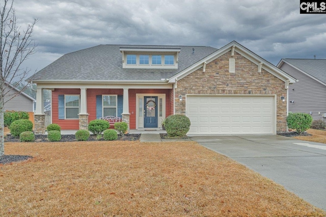 craftsman-style home featuring covered porch, a garage, and a front lawn