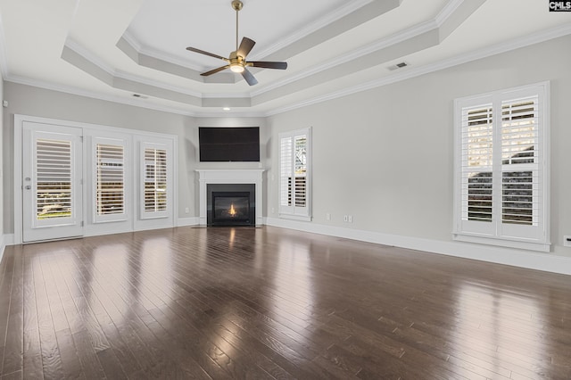 unfurnished living room with crown molding, a tray ceiling, dark wood-type flooring, and ceiling fan