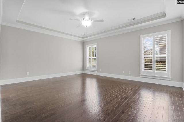 empty room with crown molding, dark wood-type flooring, ceiling fan, and a tray ceiling