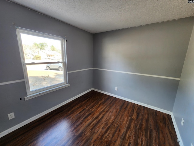 spare room with a textured ceiling and dark hardwood / wood-style flooring