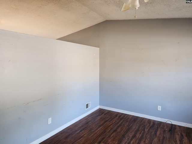 empty room with lofted ceiling, a textured ceiling, dark hardwood / wood-style floors, and ceiling fan