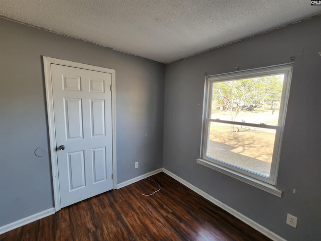 spare room featuring dark wood-type flooring and a textured ceiling