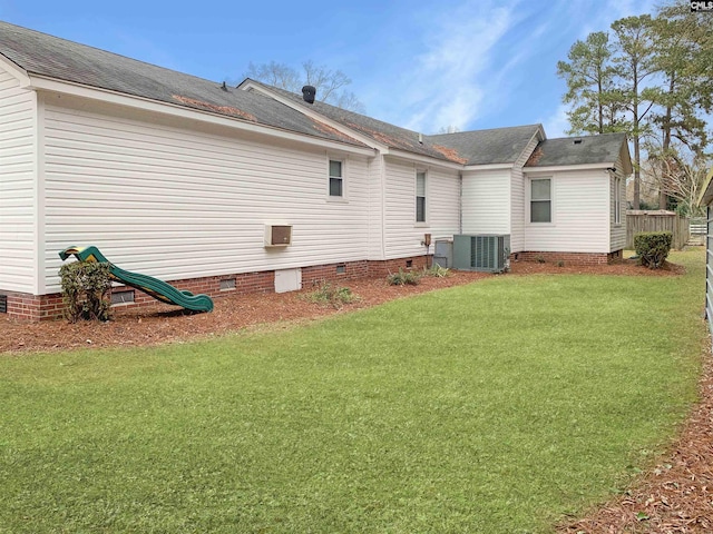 rear view of property featuring central air condition unit and a lawn