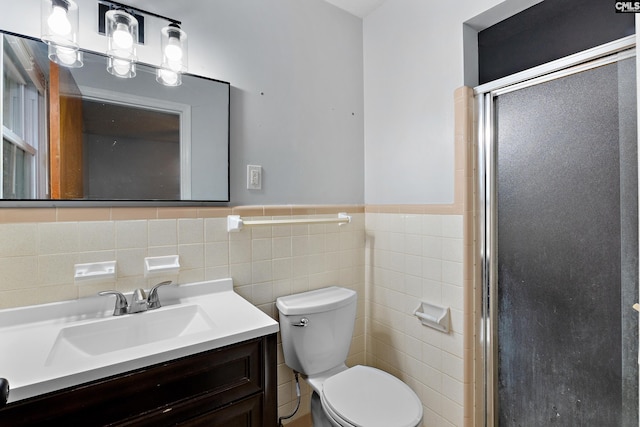 bathroom featuring vanity, a shower with door, tile walls, and toilet