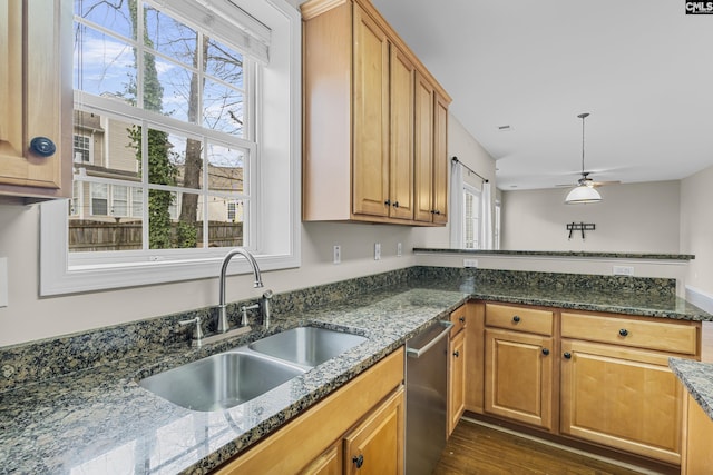 kitchen featuring sink, ceiling fan, dark stone countertops, dark hardwood / wood-style flooring, and stainless steel dishwasher