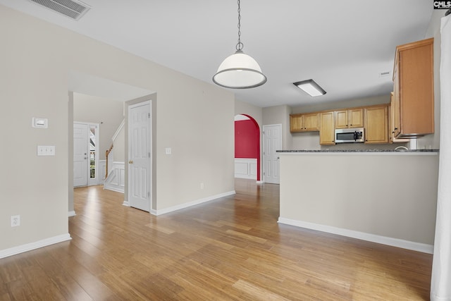 kitchen featuring pendant lighting, light brown cabinets, light hardwood / wood-style floors, and kitchen peninsula