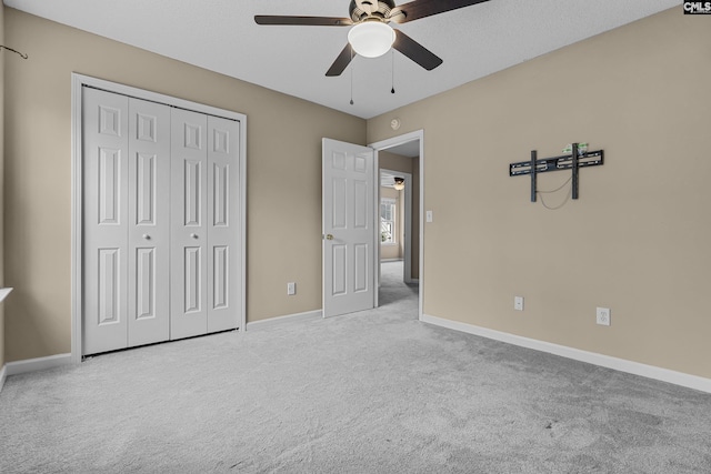 unfurnished bedroom featuring ceiling fan, light colored carpet, and a closet