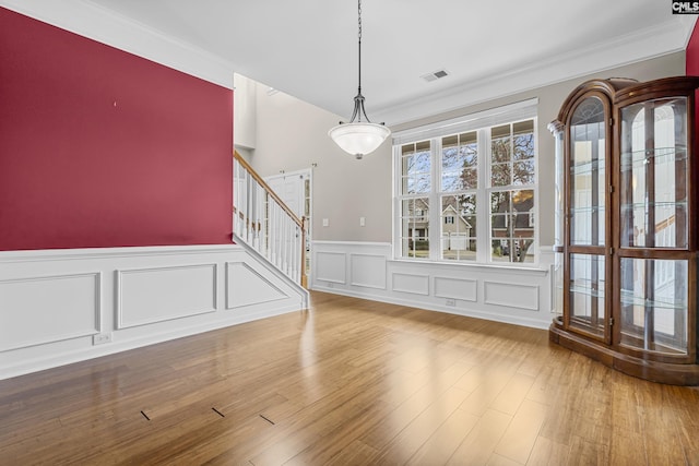 unfurnished dining area with crown molding and hardwood / wood-style flooring