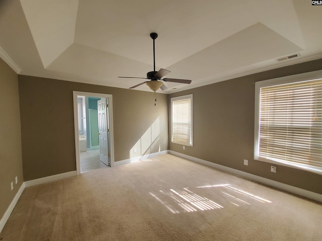 carpeted empty room featuring a tray ceiling, ornamental molding, and ceiling fan