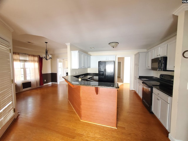 kitchen with a breakfast bar area, hanging light fixtures, black appliances, white cabinets, and light wood-type flooring