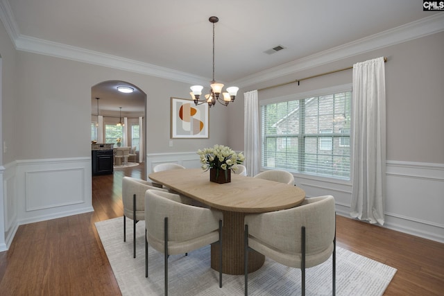 dining area with ornamental molding, dark wood-type flooring, and an inviting chandelier