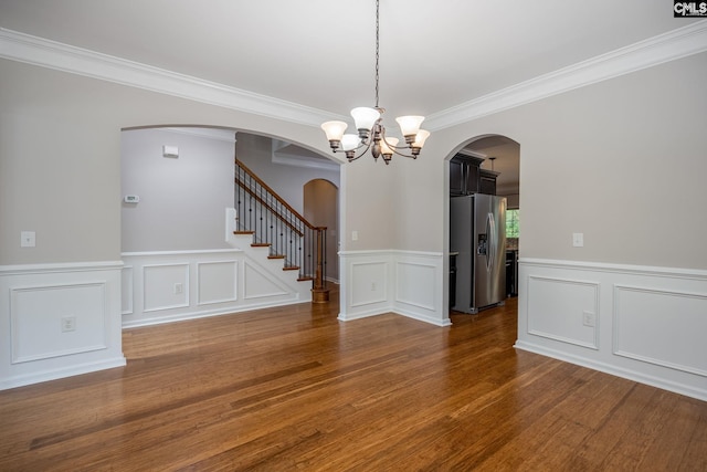 empty room featuring crown molding, hardwood / wood-style floors, and a notable chandelier