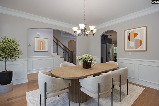 dining area with crown molding, an inviting chandelier, and light hardwood / wood-style floors