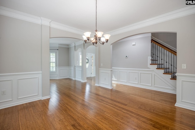 unfurnished dining area with crown molding, wood-type flooring, and a chandelier