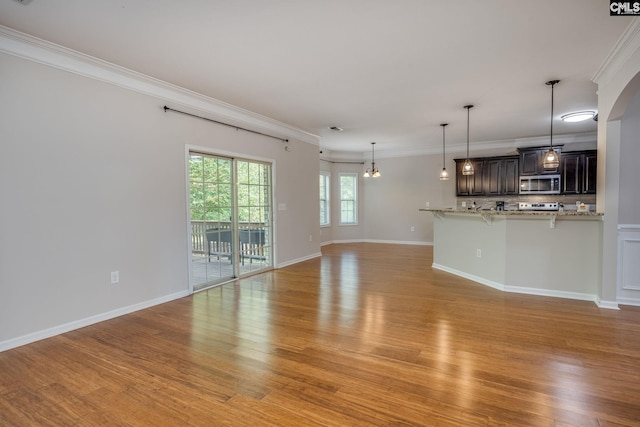 unfurnished living room featuring ornamental molding, a chandelier, and light wood-type flooring