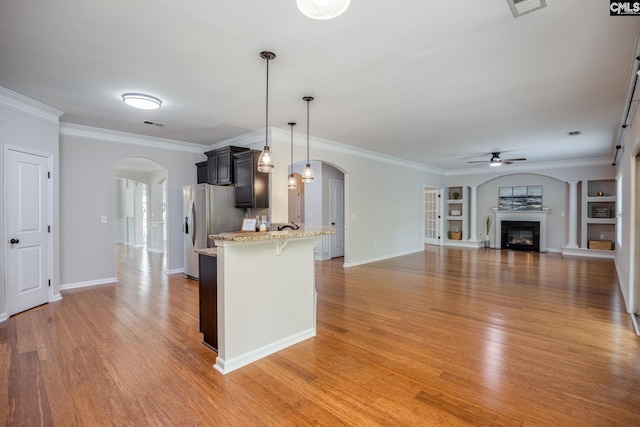 kitchen with stainless steel refrigerator with ice dispenser, a breakfast bar area, ceiling fan, and light hardwood / wood-style floors