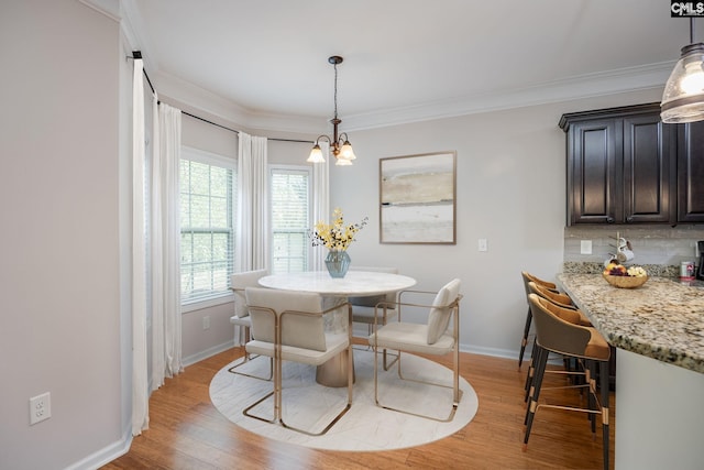 dining space with a notable chandelier, crown molding, and light wood-type flooring