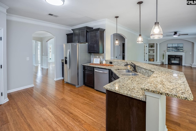 kitchen with sink, crown molding, light hardwood / wood-style flooring, appliances with stainless steel finishes, and hanging light fixtures