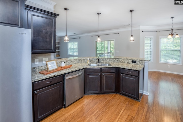 kitchen with sink, crown molding, dark brown cabinets, hanging light fixtures, and appliances with stainless steel finishes