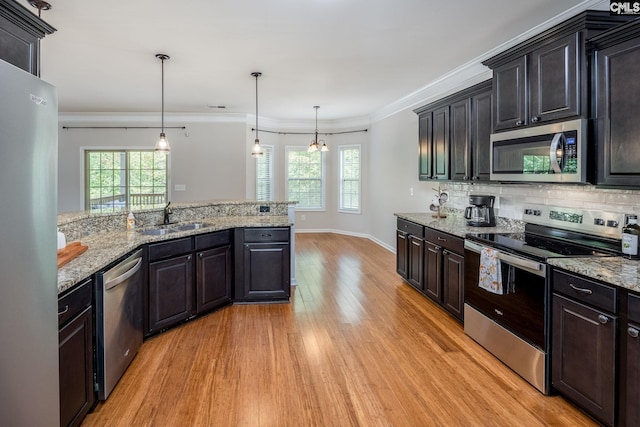 kitchen with sink, light hardwood / wood-style flooring, appliances with stainless steel finishes, hanging light fixtures, and decorative backsplash