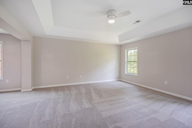 carpeted spare room with ceiling fan and a raised ceiling