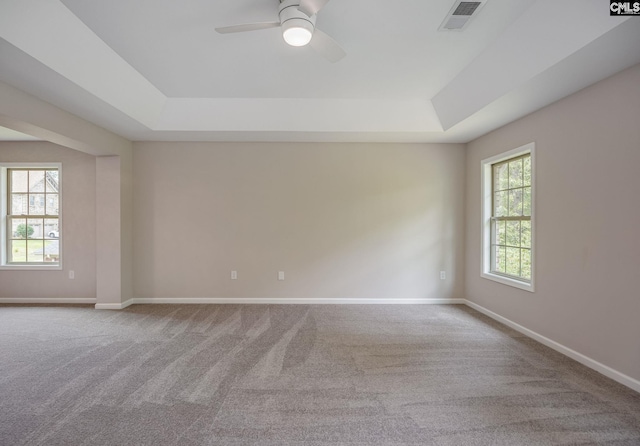 carpeted spare room featuring ceiling fan and a tray ceiling