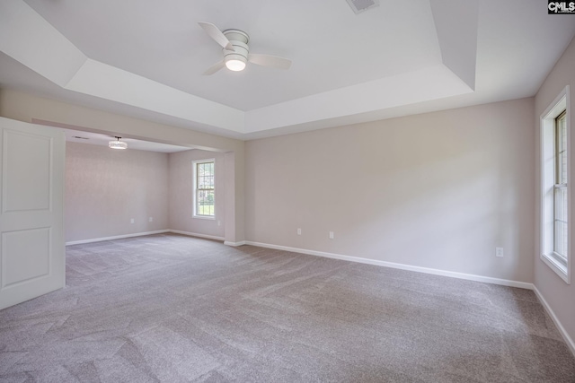 carpeted empty room featuring ceiling fan and a tray ceiling