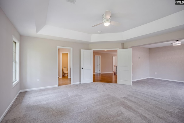 spare room with ceiling fan, light colored carpet, and a tray ceiling