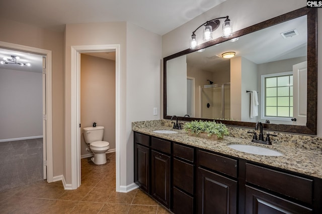 bathroom featuring vanity, a shower with door, tile patterned floors, and toilet