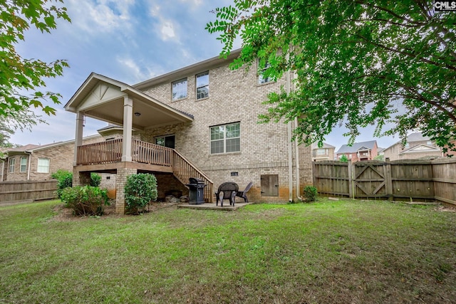 rear view of house featuring a wooden deck and a lawn