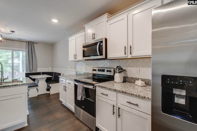 kitchen with sink, white cabinetry, light stone counters, stainless steel appliances, and decorative backsplash