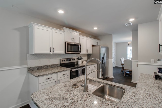 kitchen with sink, appliances with stainless steel finishes, tasteful backsplash, light stone counters, and white cabinets