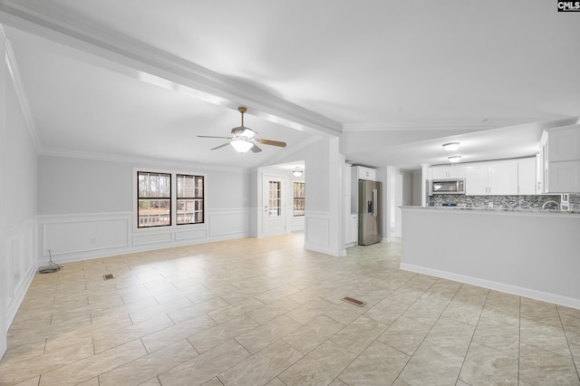 unfurnished living room with crown molding, ceiling fan, and vaulted ceiling with beams