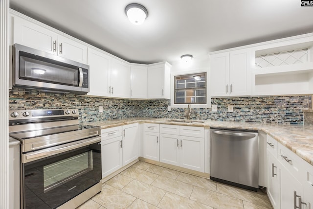 kitchen featuring tasteful backsplash, sink, white cabinets, light stone counters, and stainless steel appliances