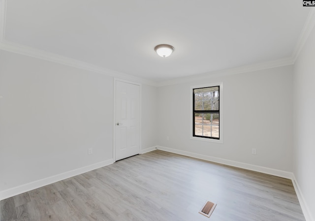 empty room with crown molding and light hardwood / wood-style flooring