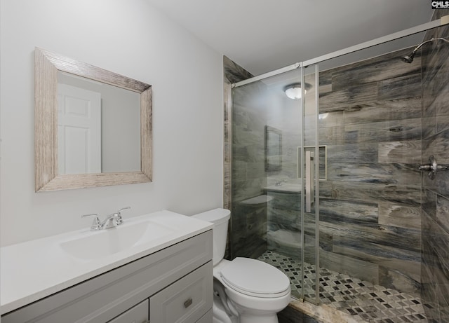 bathroom with vanity, a shower with door, and toilet