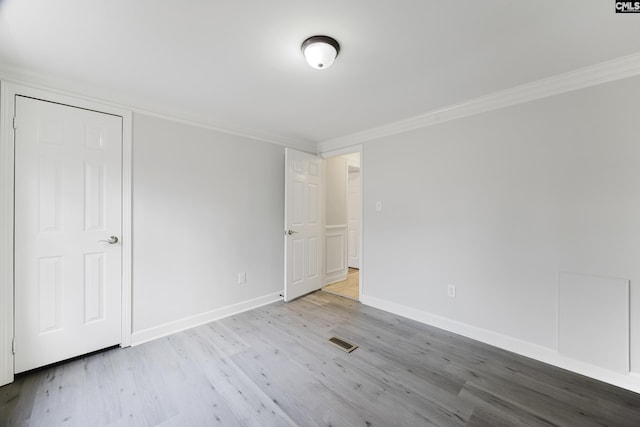 unfurnished bedroom with ornamental molding and light wood-type flooring