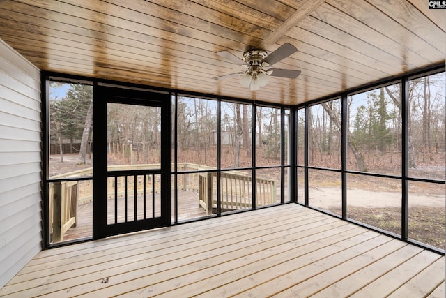 unfurnished sunroom featuring wood ceiling, ceiling fan, and a healthy amount of sunlight