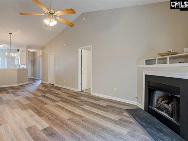 unfurnished living room featuring ceiling fan with notable chandelier, high vaulted ceiling, and wood-type flooring