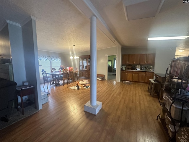 living room with decorative columns, wood-type flooring, a textured ceiling, and a chandelier