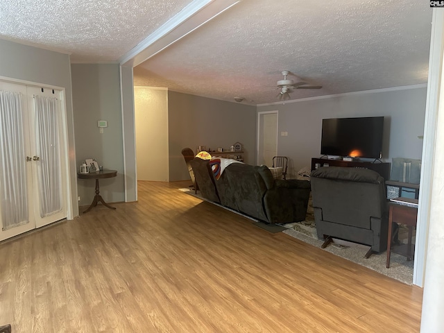 living room with crown molding, ceiling fan, a textured ceiling, and light hardwood / wood-style floors