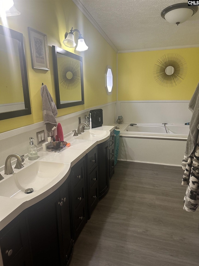 bathroom featuring a bathtub, hardwood / wood-style flooring, vanity, crown molding, and a textured ceiling