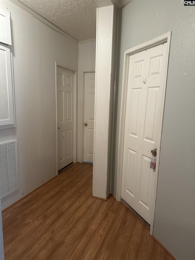 unfurnished bedroom featuring crown molding, a textured ceiling, and light wood-type flooring