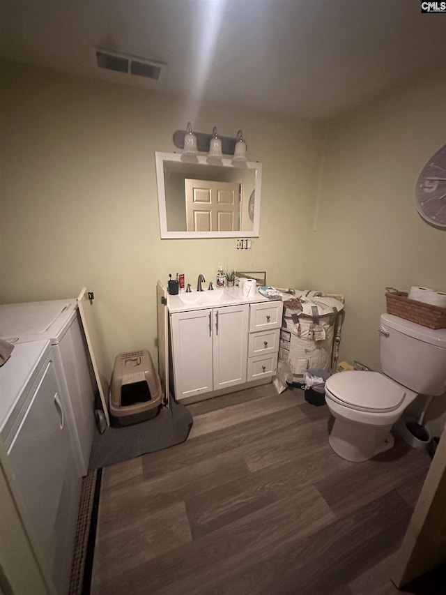 bathroom featuring vanity, hardwood / wood-style floors, toilet, and washing machine and clothes dryer